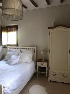 a bedroom with a bed with white sheets and a lamp at Masia Quelet in La Vall de Bianya
