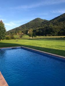 a blue swimming pool with mountains in the background at Masia Quelet in La Vall de Bianya