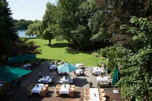 einen Blick über ein Restaurant mit Tischen und Sonnenschirmen in der Unterkunft Landhaus am See in Garbsen