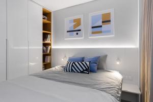 a white bedroom with a bed and a book shelf at Apartament Bielany 3 min from metro with 5-meals per day customisable diet catering and free parking in Warsaw