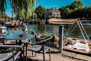 Bistrotel 't Amsterdammertje في Nieuwersluis: طاولة وكراسي بجوار نهر مع قارب