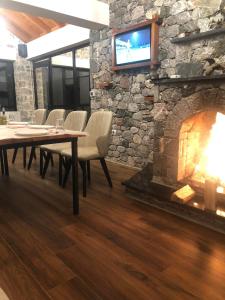 a dining room with a fireplace and a tv on a stone wall at Bujtina Vrenezi in Peshkopi