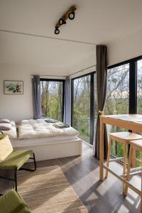 a bedroom with a bed and a table and windows at Stüble Kabinok in Somogyhárságy