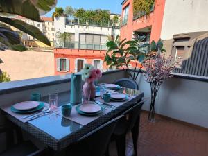 a table on a balcony with plates and flowers on it at Cozy Apartment with large exclusive terrace in Milan