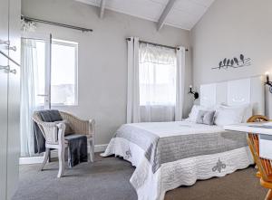 a bedroom with a bed and a chair and a window at 138 Marine Beachfront Guesthouse in Hermanus