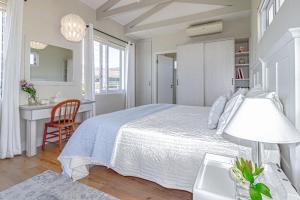 a white bedroom with a bed and a desk at 138 Marine Beachfront Guesthouse in Hermanus