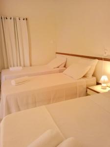um quarto com três camas e uma mesa com um candeeiro em Pousada Aruamar em Aracaju