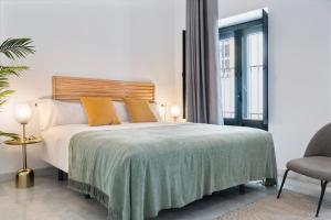 een slaapkamer met een groot bed en een stoel bij Suites Maestranza - Refinadores by Magno Apartments in Sevilla