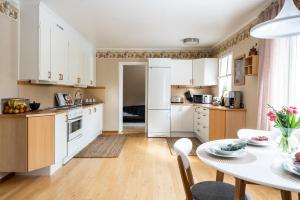 a kitchen with white cabinets and a table and chairs at Munksund Apartments Villa in Piteå