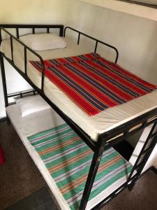 a metal bunk bed with a striped blanket on it at Drop Hostel in Kandy