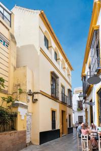 een groep mensen aan een tafel buiten een gebouw bij Suites Maestranza - Refinadores by Magno Apartments in Sevilla