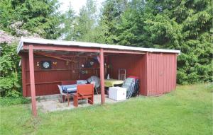 a red shed with a table and chairs in a yard at 2 Bedroom Beautiful Home In Herning in Kølkær