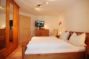 a bedroom with a white bed and a television at Ferienwohnungen Neuhausenlehen in Ramsau