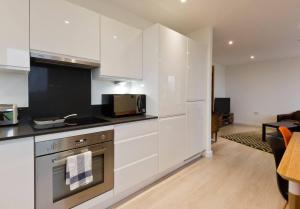 cocina con armarios blancos y fogones en 2-Bed Apartment only 15 mins from Central London, en Londres