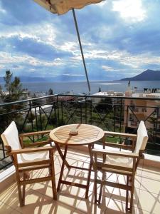 una mesa y sillas en un balcón con vistas al océano en Nefeli Studios, en Loutra Edipsou