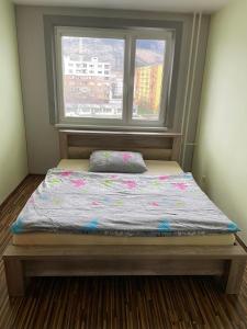a bed sitting in a room with a window at Apartman Gufo in Kysucké Nové Mesto