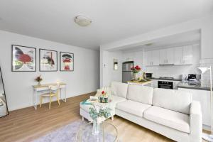 a living room with a white couch and a kitchen at Romantic Retreat with Garden in Melbourne +7 photos