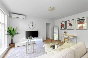 a white living room with a couch and a tv at Romantic Retreat with Garden in Melbourne