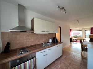 - une cuisine avec des placards blancs et un évier dans l'établissement Große Ferienwohnung, Apartment in Leimen WeHome Komfort, à Leimen