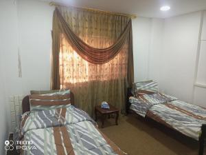 Cette chambre comprend deux lits et une fenêtre avec un rideau. dans l'établissement Baiet AL-Deafah Guest house, à Um Qeis