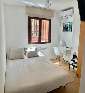 a bedroom with a bed and a desk and a window at Habitación González in Málaga