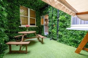 d'une terrasse avec une table, des bancs et un mur vert. dans l'établissement Luxury Apartment in the heart of Central London, à Londres