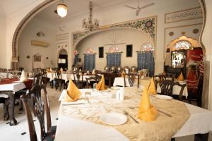 ein Esszimmer mit Tischen und Stühlen mit gelben Servietten darauf in der Unterkunft Khandela Haveli - a Boutique Heritage Hotel in Jaipur
