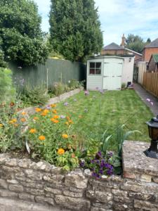 einen Garten mit einer Steinmauer und Blumen in der Unterkunft 200m AOSB Cottage in Westbury in Westbury