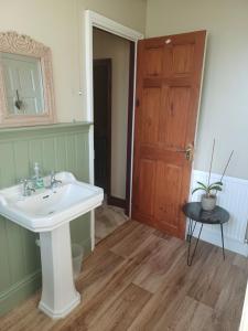 a bathroom with a white sink and a wooden door at 200m AOSB Cottage in Westbury in Westbury