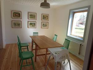 a dining room with a wooden table and green chairs at original Schwedenhaus in Borghamn