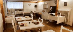 uma cozinha com mesas brancas e cadeiras num quarto em Pension TTT em Bled