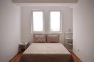 a small bedroom with a bed with two windows at Charming & Spacious 2 Bedroom Apartment with a Gorgeous 8th-floor view in Ohrid +3 photos