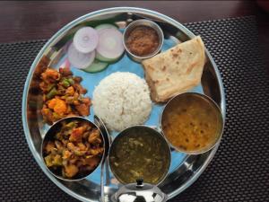 a plate of food with rice and different types of food at Unique Hotel and Lodge - Pleasure of Homely Stay - in Bandīpur