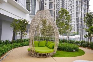 a rattan chair with green pillows in a courtyard at Cyberjaya Eclipse 5 Plus 2 PAX Blissful Suite in Cyberjaya