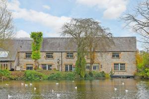 an old stone house with a pond in front of it at Woodmill Bakewell Riverside in Bakewell