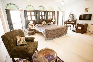 een slaapkamer met een bed, een bank en een stoel bij Khandela Haveli - a Boutique Heritage Hotel in Jaipur