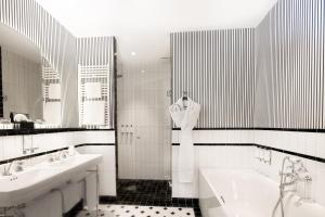 a black and white bathroom with two sinks and a bath tub at The 1932 Hotel & Spa Cap d'Antibes - MGallery Collection in Juan-les-Pins