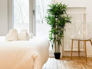 een slaapkamer met een wit bed en een plant bij Marquis proche du centre ville in Annecy