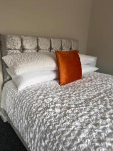 a bed with an orange pillow on top of it at The Coral 66 Guest House Southampton in Southampton