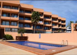 a swimming pool in front of a building at Amazing seafront apt in playa den bossa in Playa d'en Bossa