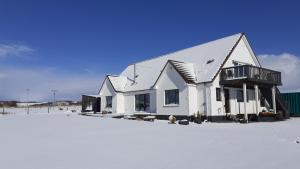 una casa blanca sentada sobre un campo cubierto de nieve en Achalochan House, en Ose