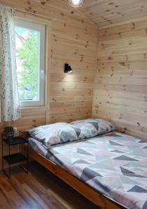 a bedroom with a bed in a wooden room at Owocowe Wakacje - Domek nad jeziorem in Mikołajki