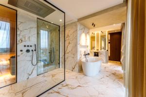 een badkamer met een bad, een douche en een wastafel bij The CORNR Hotel in Nieuwpoort