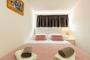 a bedroom with a bed with pink pillows and a window at Stipe in Obuljeno