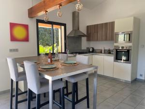 eine Küche mit einem Holztisch und Stühlen in der Unterkunft "Les cigales" aux portes de la Provence in Bollène