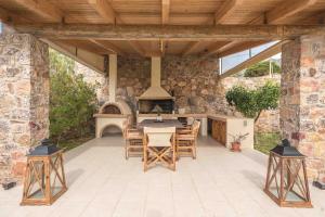 une cuisine extérieure avec une table et des chaises sur une terrasse dans l'établissement Anavissos 3bdr Seaview Beachhouse with Bbq, à Anavyssos