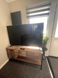 a large flat screen tv sitting on a wooden entertainment center at The Coral 66 Guest House Southampton in Southampton