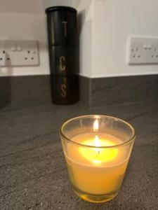 a candle in a glass sitting on a counter at East London penthouse views 2bd in Barking