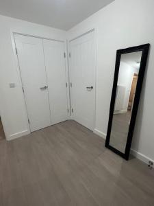 a room with white cabinets and a mirror at East London penthouse views 2bd in Barking