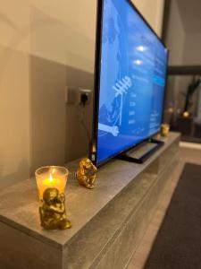 a television and a candle on a table at East London penthouse views 2bd in Barking